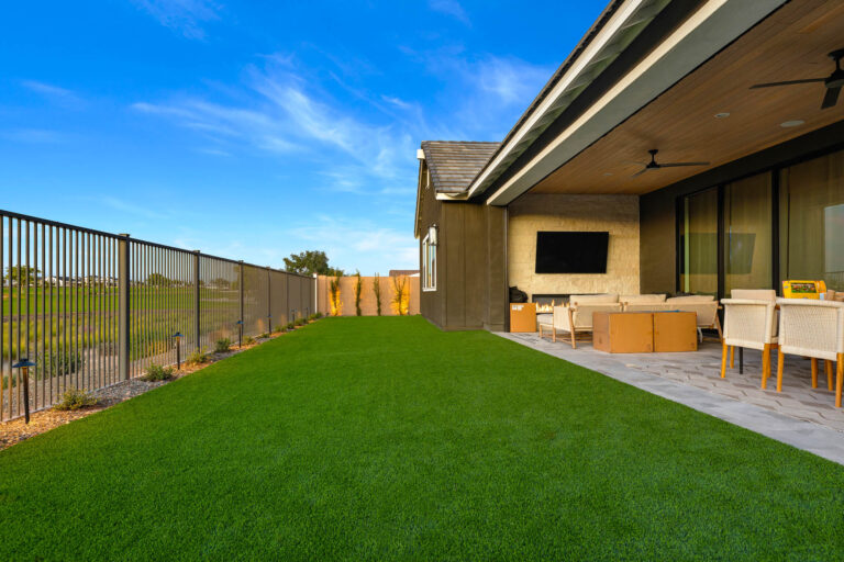 Artificial turf backyard beside a covered patio with outdoor seating