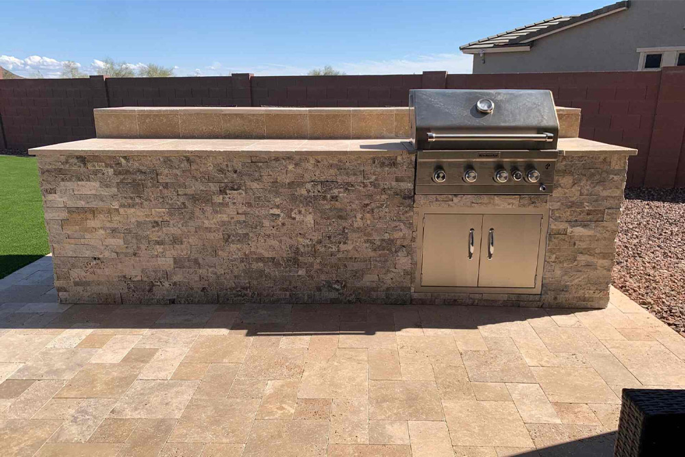 Outdoor kitchen and backyard living area designed by Diamond Stone and Synthetic Grass